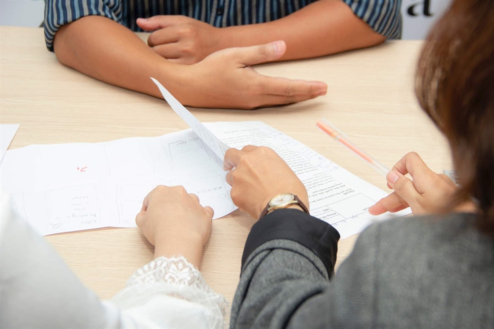 arms of three people filling out application at desk